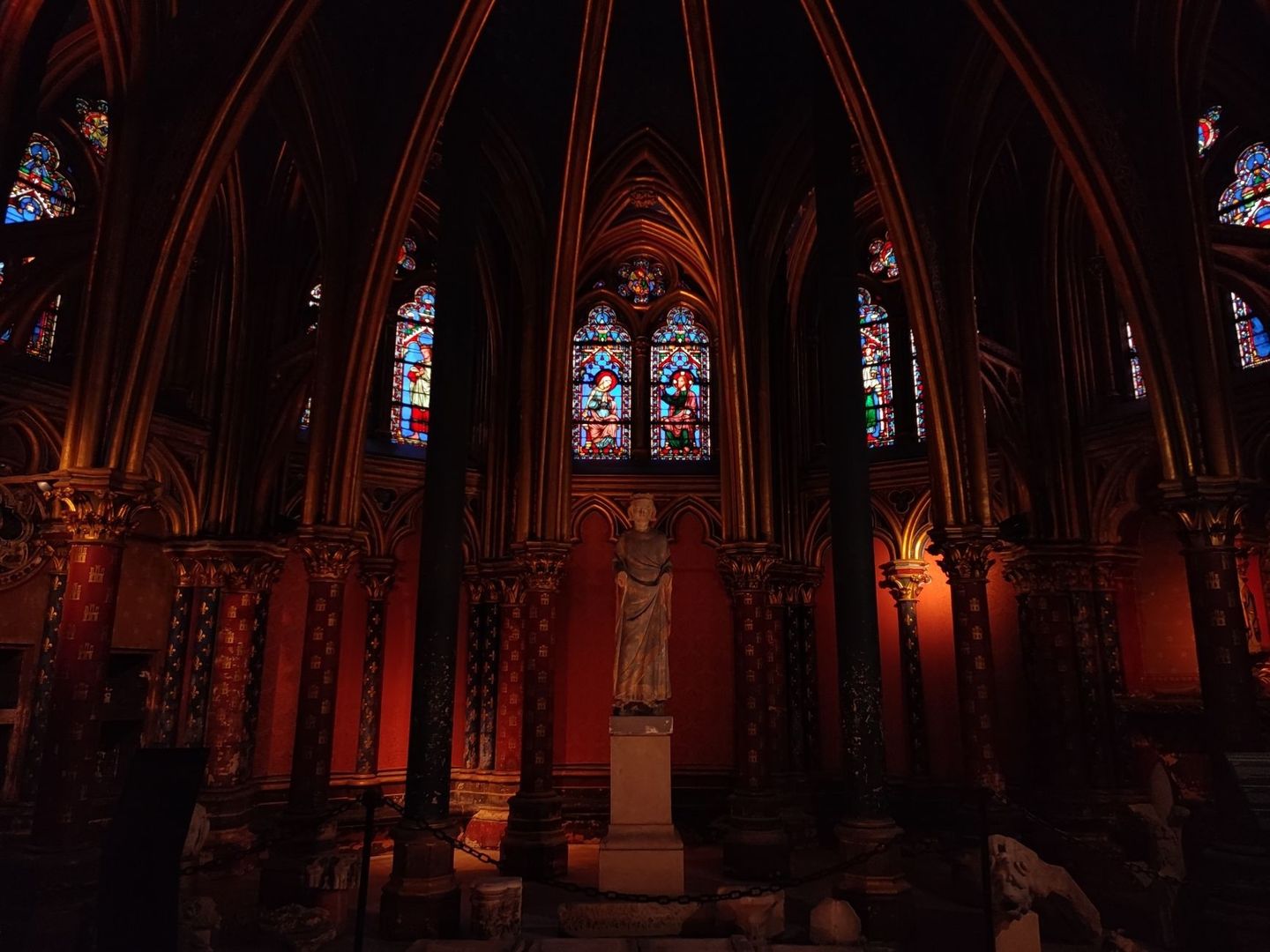 Intérieur gothique sombre avec statue et vitraux médiévaux colorés